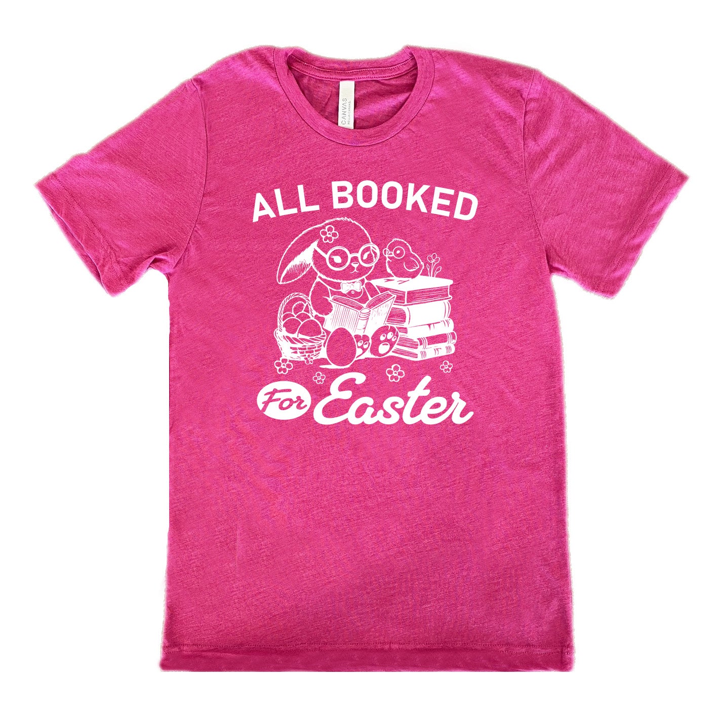 berry unisex tee with the words "all booked for Easter" on it, and the graphic of a bunny wearing glasses and a bowtie, reading a book, next to a stack of books (with a bird wearing glasses on top of it) on one side, and a basket of eggs on the other side