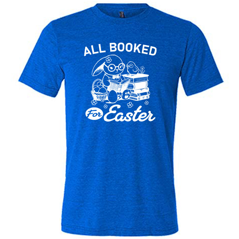 blue unisex tee with the words "all booked for Easter" on it, and the graphic of a bunny wearing glasses and a bowtie, reading a book, next to a stack of books (with a bird wearing glasses on top of it) on one side, and a basket of eggs on the other side