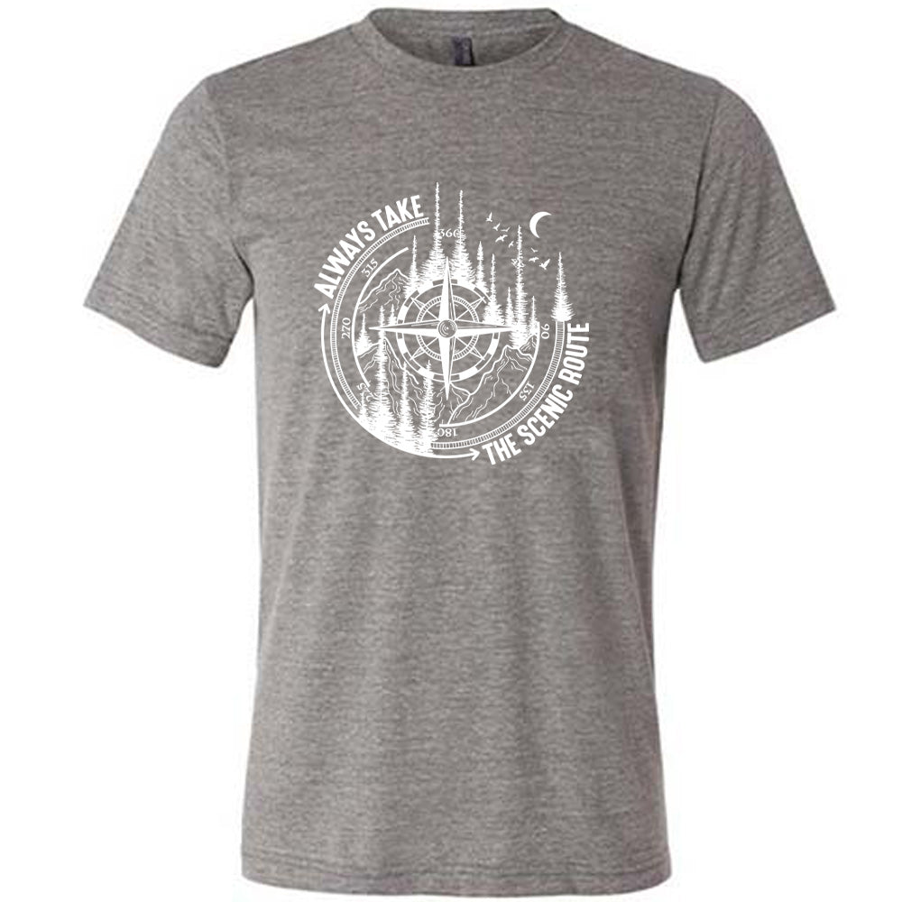 Grey colored shirt with a compass and forest graphic on it that says "Always Take The Scenic Route"
