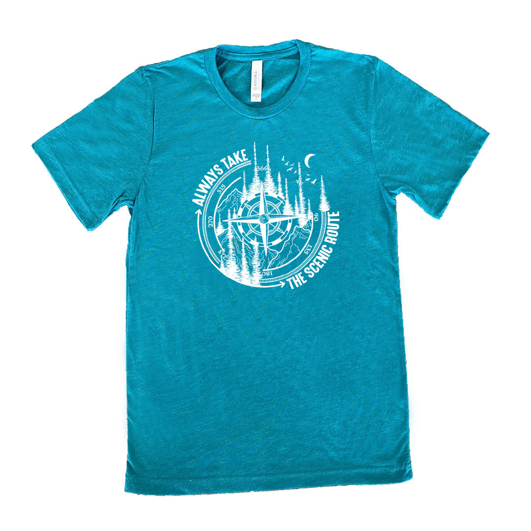 Teal colored shirt with a compass and forest graphic on it that says "Always Take The Scenic Route"