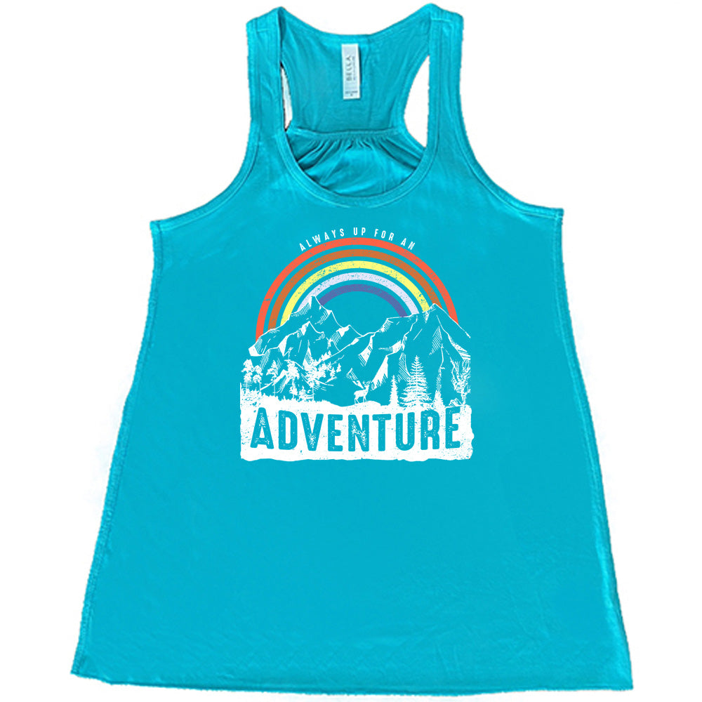 Teal colored flowy tank with a rainbow over mountains graphic on it that says "Always Up For An Adventure"