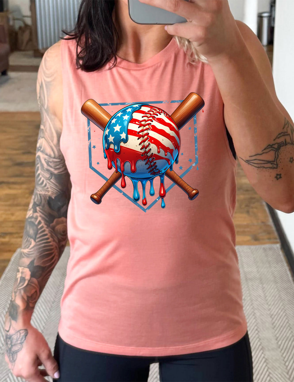 peach muscle tank with the graphic of a baseball painted (and dripping) with the American flag, and two baseball bats crossed behind it, all in front of a starry baseball diamond