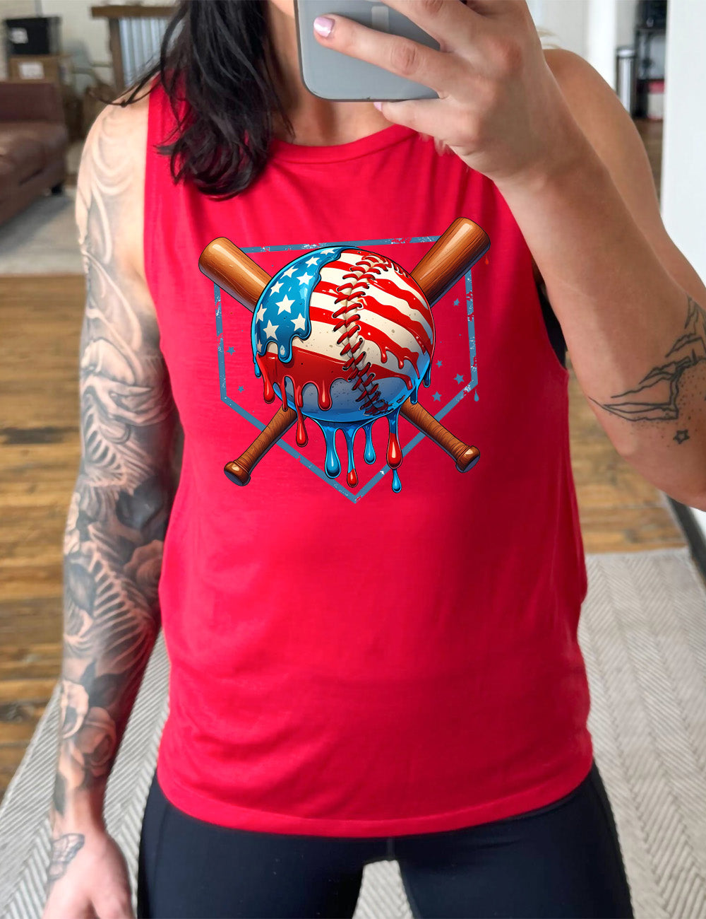 red muscle tank with the graphic of a baseball painted (and dripping) with the American flag, and two baseball bats crossed behind it, all in front of a starry baseball diamond