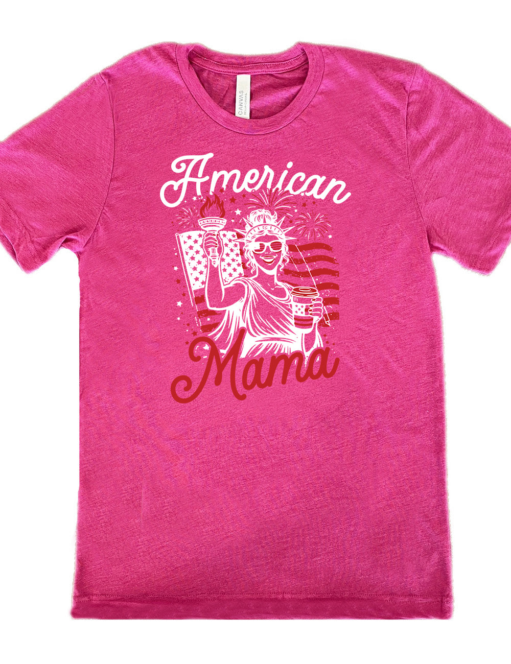 berry unisex tee with the graphic of the statue of liberty in front of an American flag, fireworks above, wearing American flag sunglasses, holding a American flag coffee cup, with the words "American Mama" surrounding it