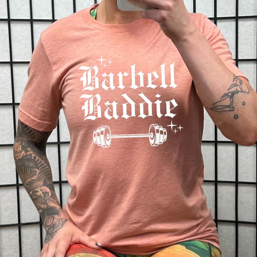 peach shirt with the text "Barbell Baddie" on it