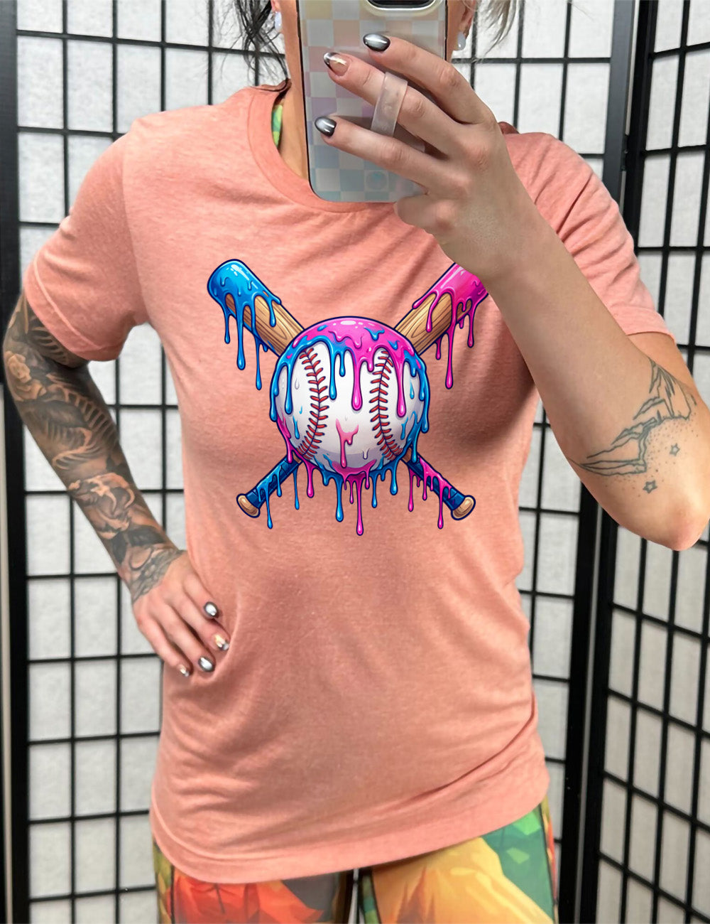 sunset unisex tee with the graphic of a baseball with two bats crossed behind it, and all of it dripping with blue and pink