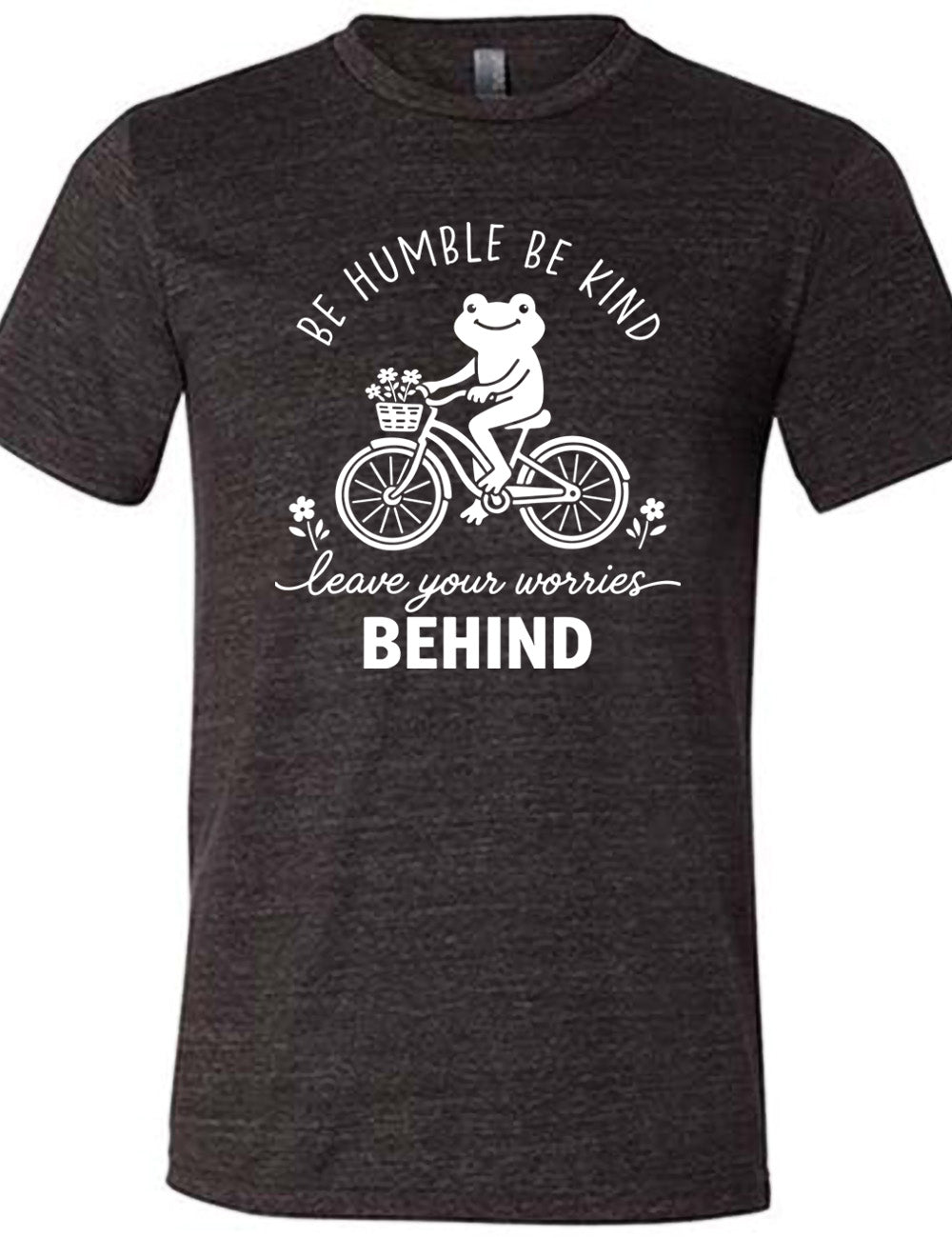 black unisex tee with the graphic of a happy frog riding a bike that has a basket of flowers attached, with a flower in front and behind the bike, and the wording arching above and ending below saying "be humble be kind leave your worries BEHIND"