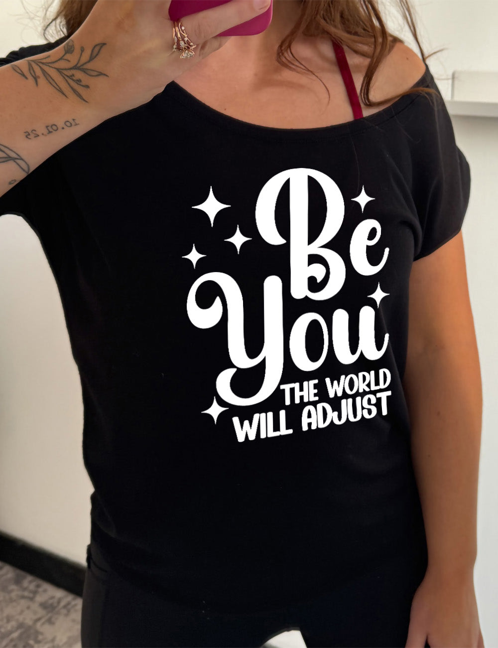 black slouchy tee with the words "be you" in big letters, surrounded by a few little stars, followed by the words "the world will adjust" underneath