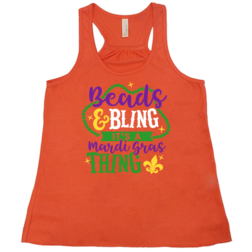 coral flowy tank with the words "beads & bling it's a mardi gras thing" on it, with graphics of a ring of beads around part of the words and a few stars as well as a fleur-de-lis symbol