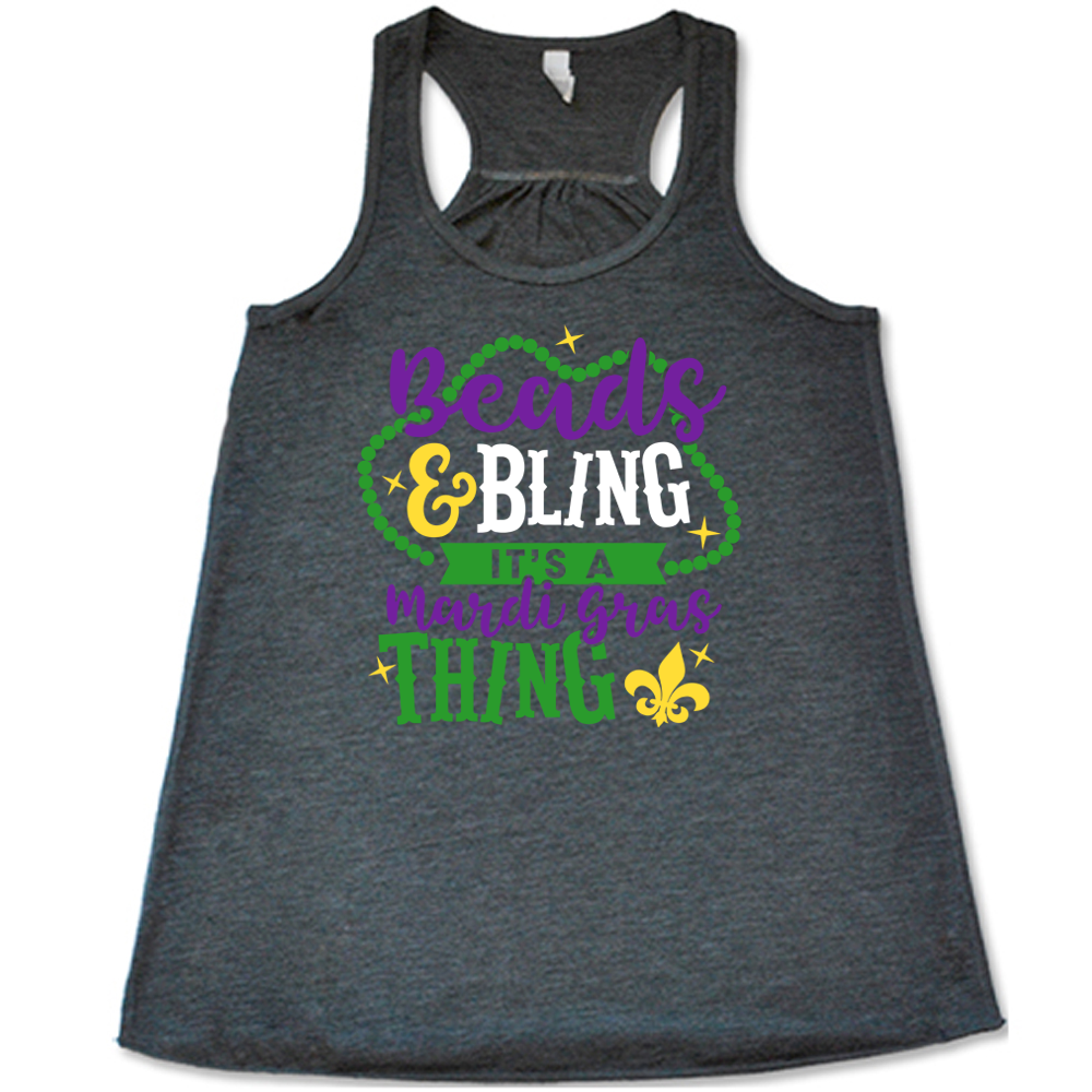 grey flowy tank with the words "beads & bling it's a mardi gras thing" on it, with graphics of a ring of beads around part of the words and a few stars as well as a fleur-de-lis symbol