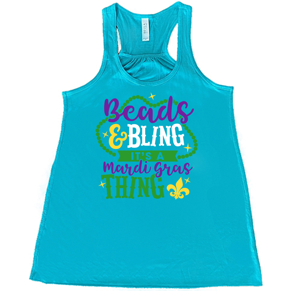 teal flowy tank with the words "beads & bling it's a mardi gras thing" on it, with graphics of a ring of beads around part of the words and a few stars as well as a fleur-de-lis symbol