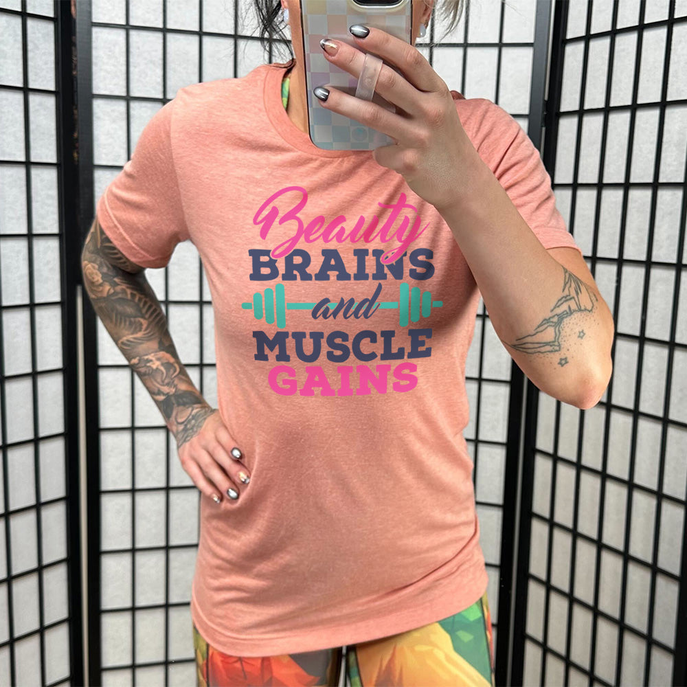 Sunset Unisex Tee, with wording Beauty Brains and Muscle Gains, multicolored lettering with a barbell