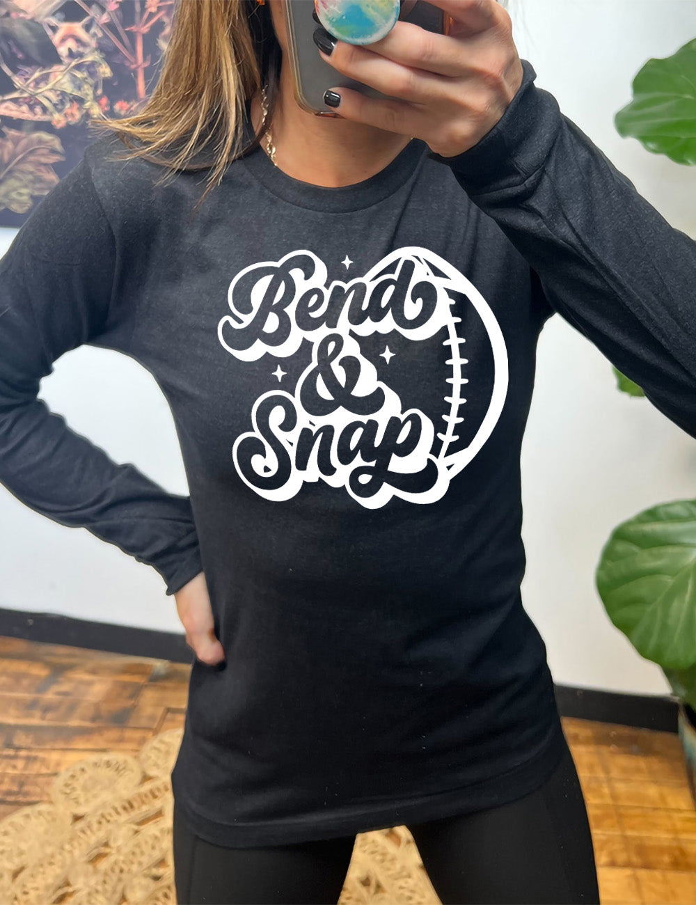 heather black long sleeve tee with the words in cursive saying "Bend & Snap" with the outline graphic of a football slightly underneath