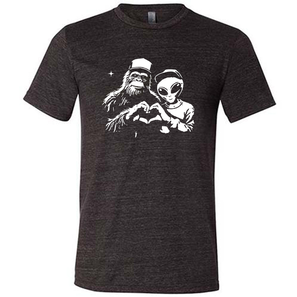 Black colored shirt with bigfoot and alien doing heart hands graphic on it