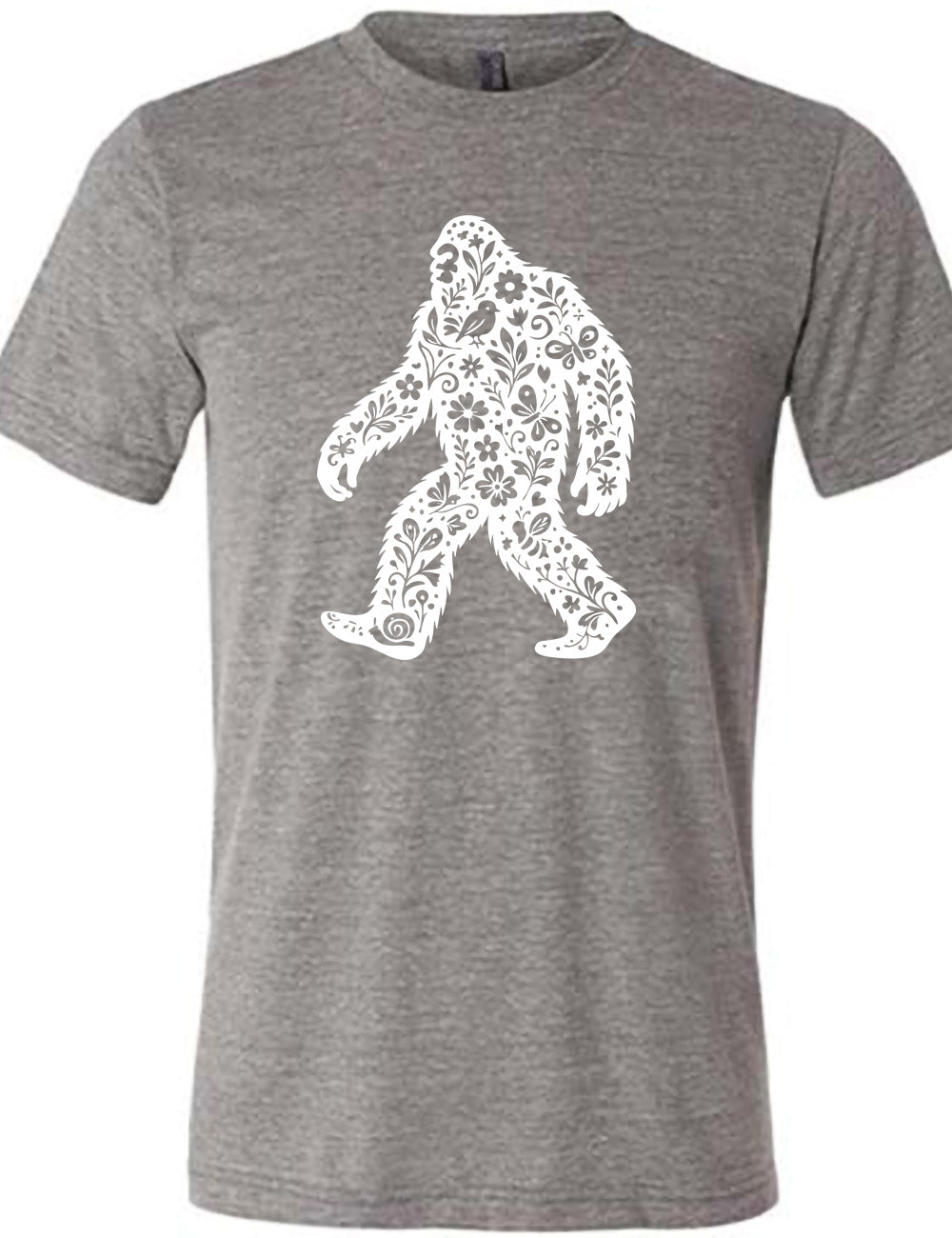 grey unisex tee with the graphic white cutout of bigfoot, which is overlayed with black flowers, plants, birds, bees, snails, and butterflies