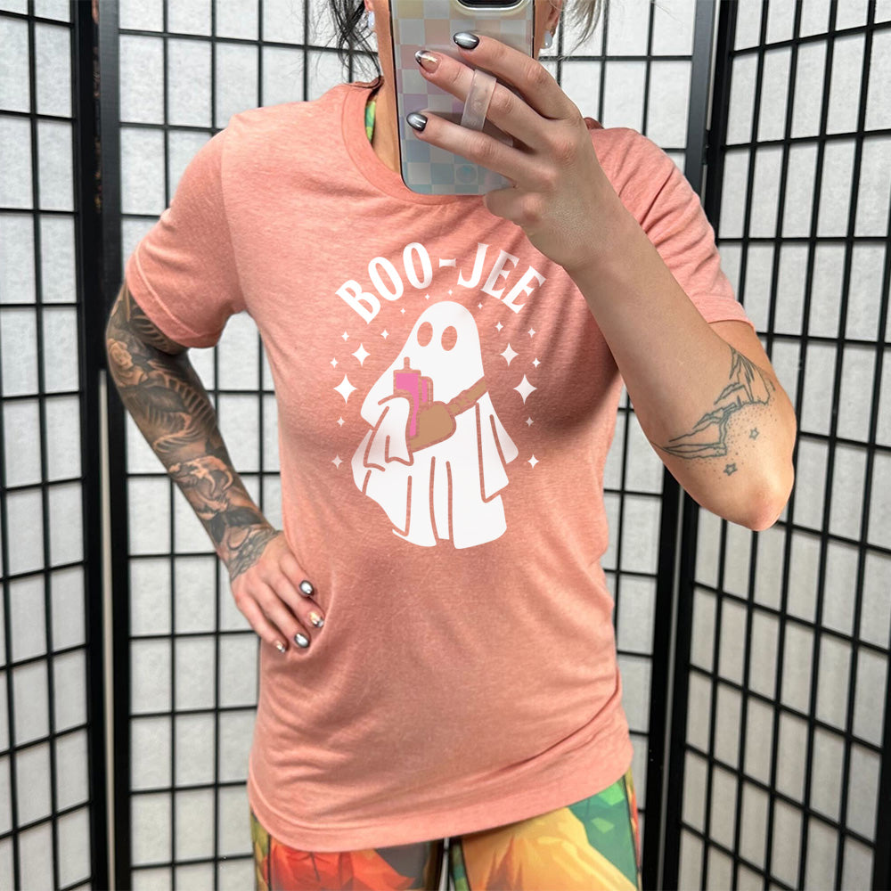 Model wearing sunset colored shirt with ghost holding drink graphic on it that says "Boo-Jee"