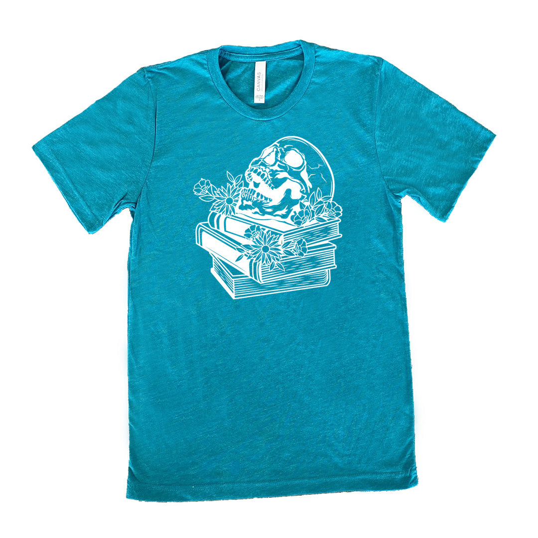teal unisex tee with the graphic of an open-mouthed skull atop a stack of books, with flowers