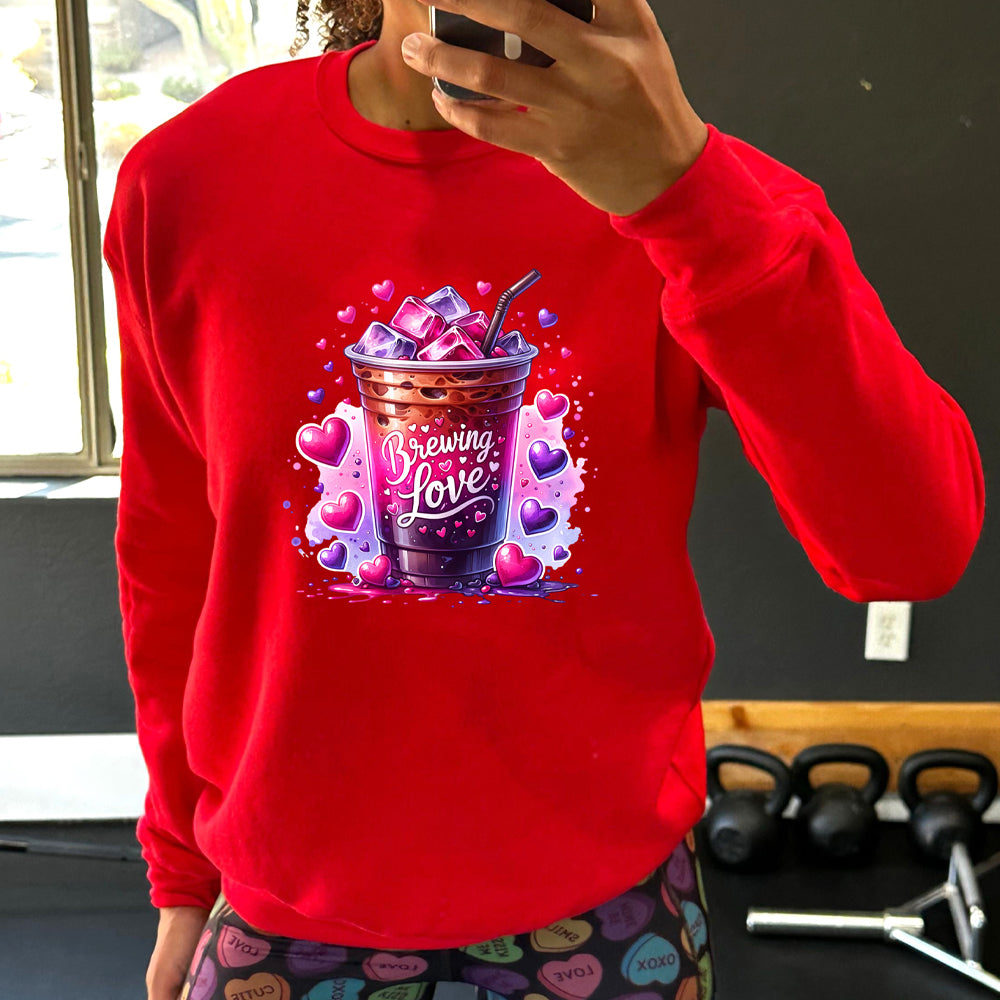 red crewneck with a graphic of iced coffee and the text "brewing love" on it