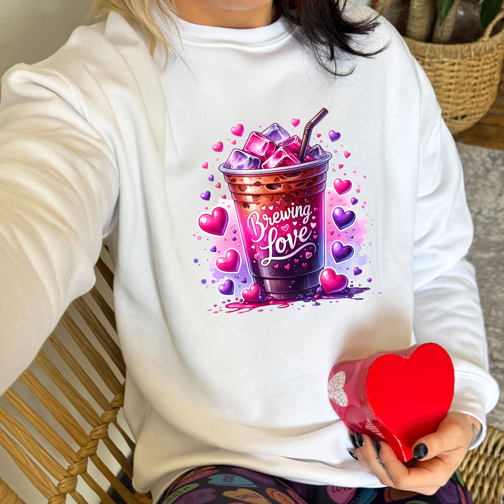 white crewneck with a graphic of iced coffee and the text "brewing love" on it