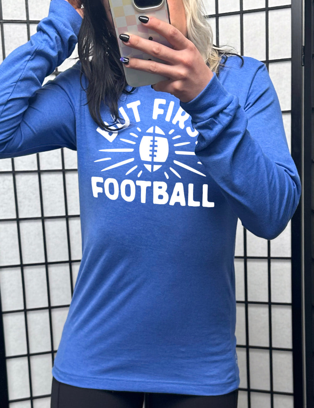 heather true royal long sleeve with the words "but first football" in capital font, with "But first" arching over the graphic of a football, with rays beaming off of it