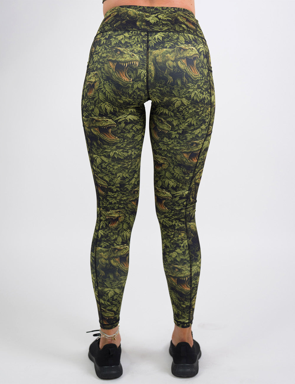 back of the full length t-rex in a forest leggings against a white background