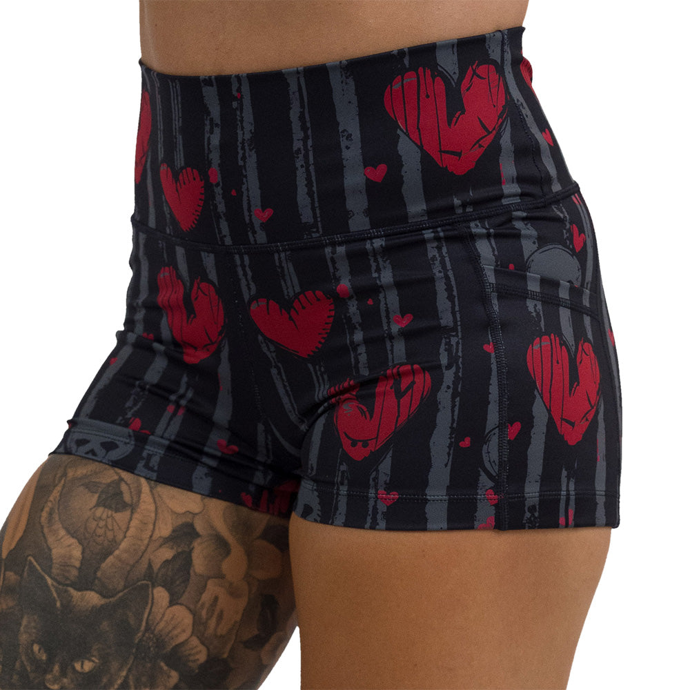 close up of the 2.5 inch red heart and gray skulls against a black and grey striped background shorts against a white background