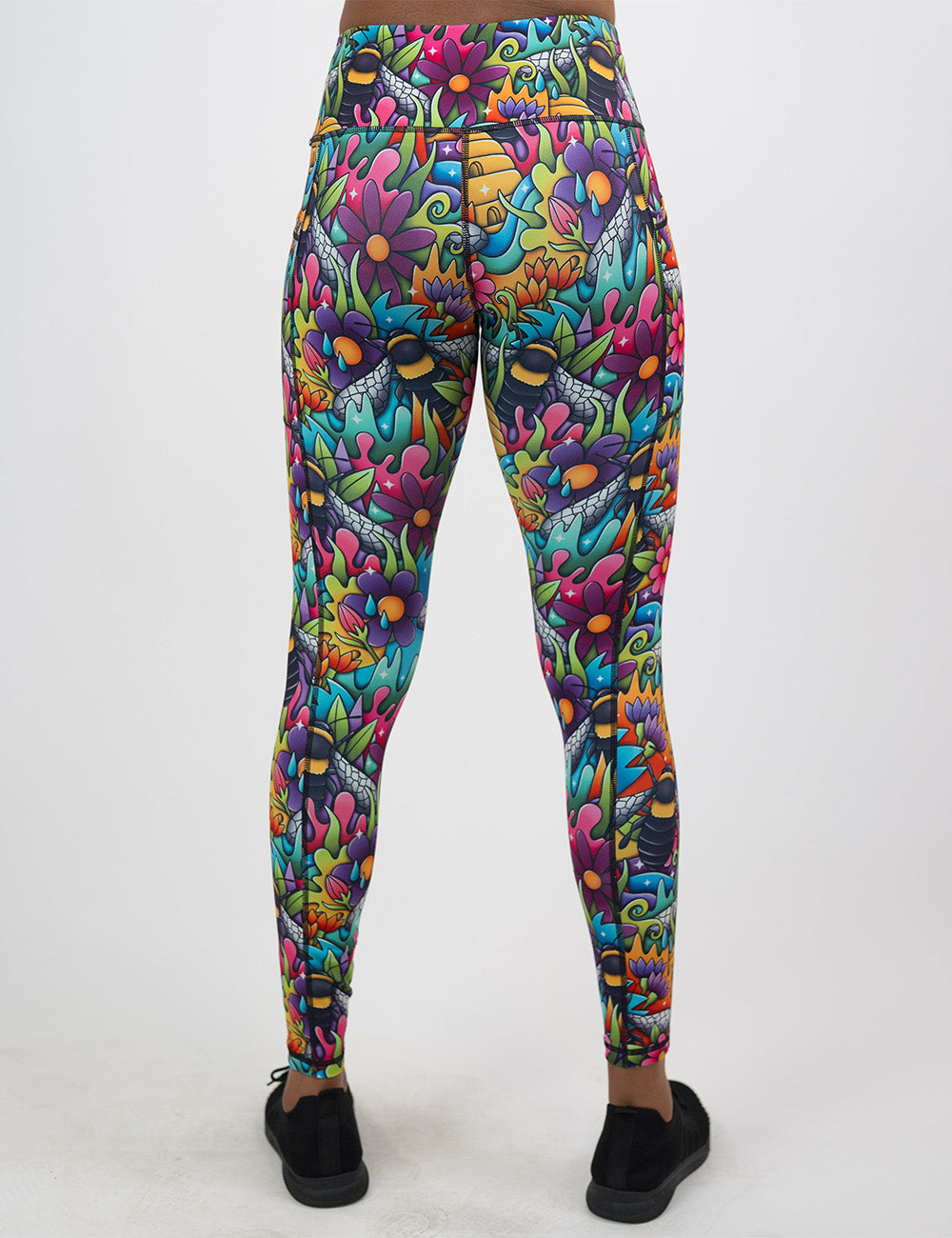 back of the full length cartoon bees against bold colorful cartoon flowers pattern leggings against a white background