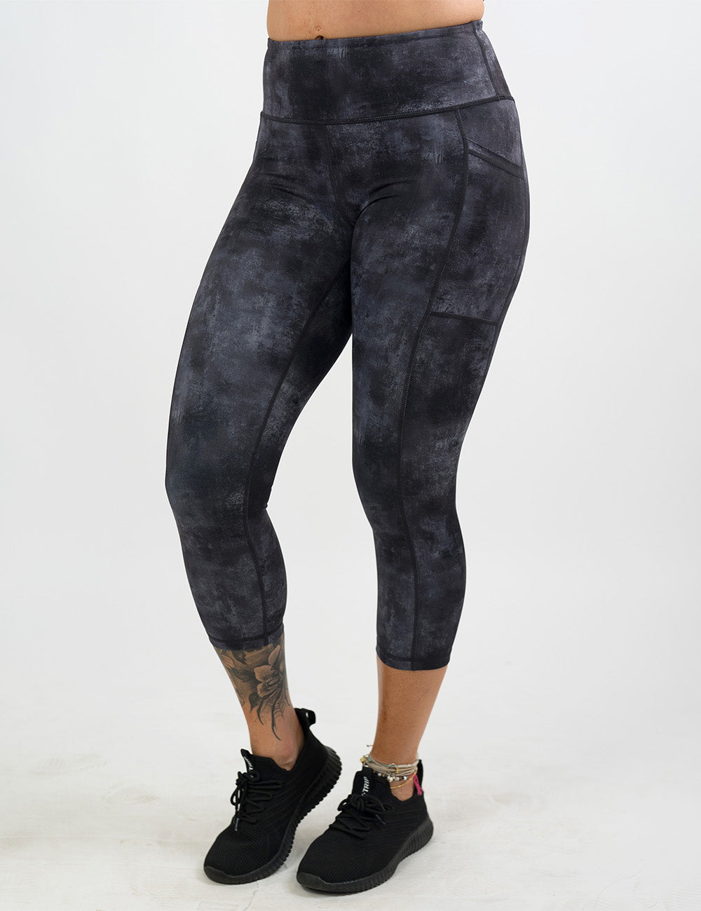 front of the black and grey grunge concrete pattern capri leggings against a white background