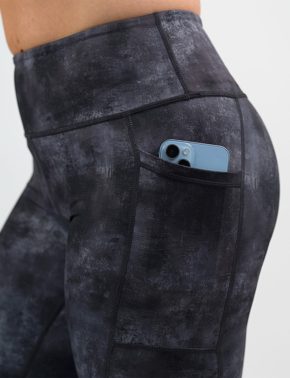 close up of the black and grey grunge concrete pattern leggings with a phone in its pocket