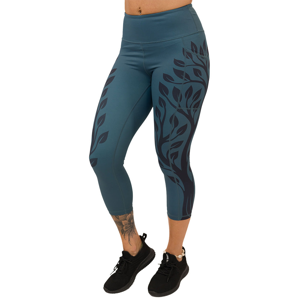 Teal leggings with black leaf pattern on a white background
