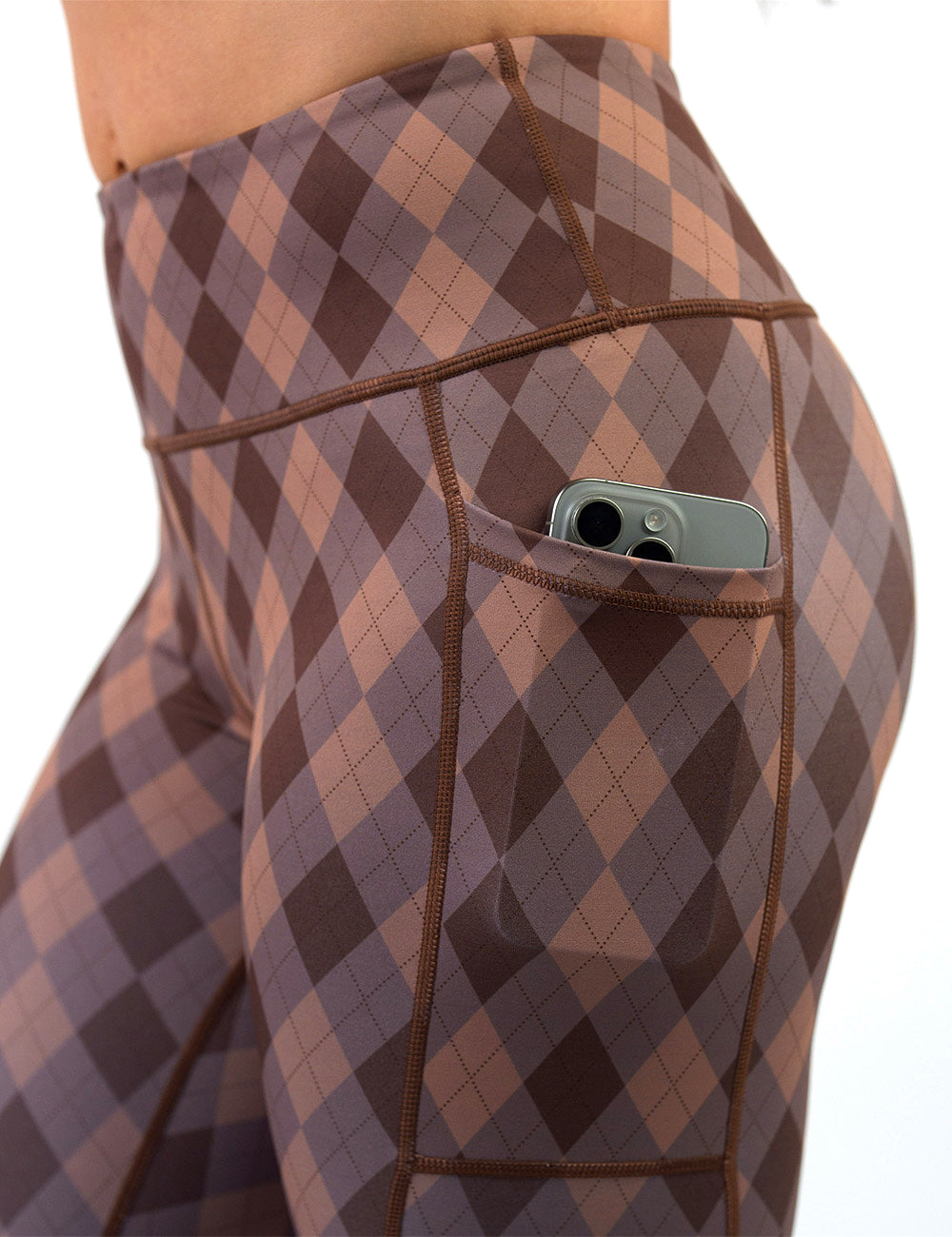 close up of the grey, beige, and dark red plaid leggings with a phone in its pocket