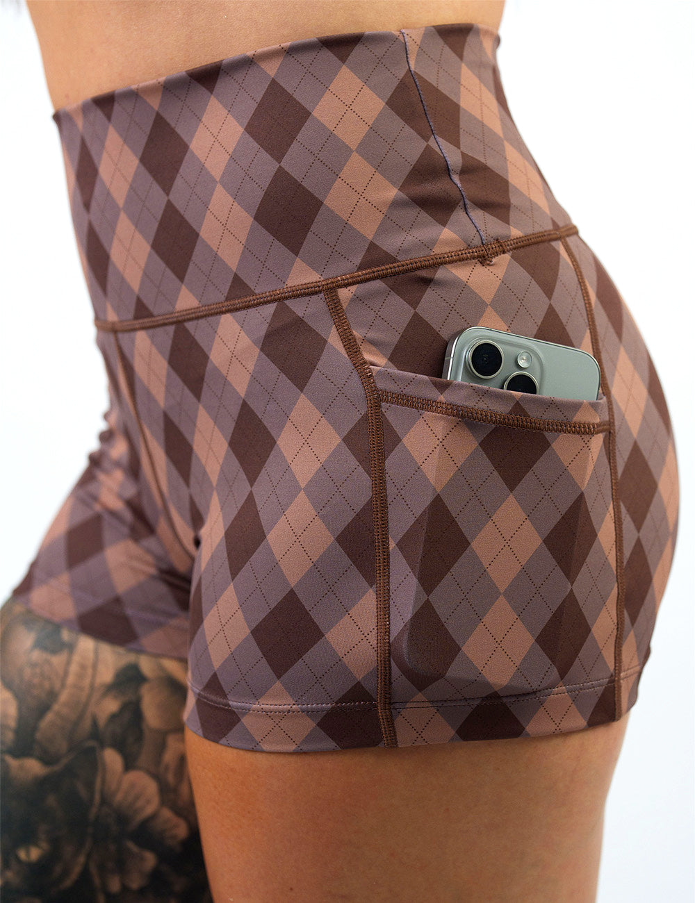 close up of the 2.5 inch beige, grey, and brown plaid shorts with a phone in its pocket