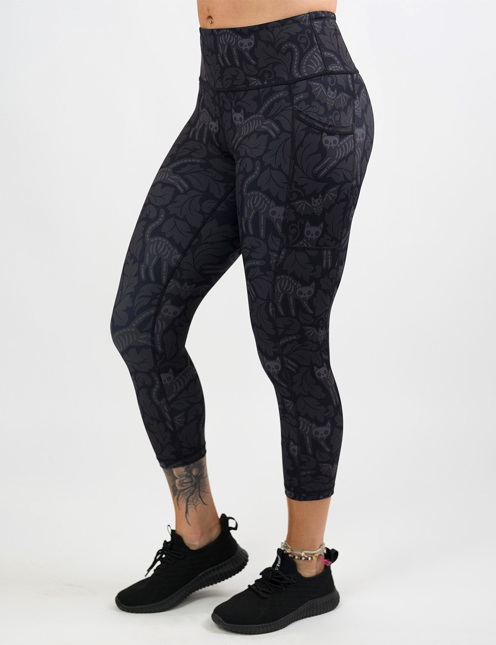 front of the black and grey bats and cats skeletons capri leggings against a white background