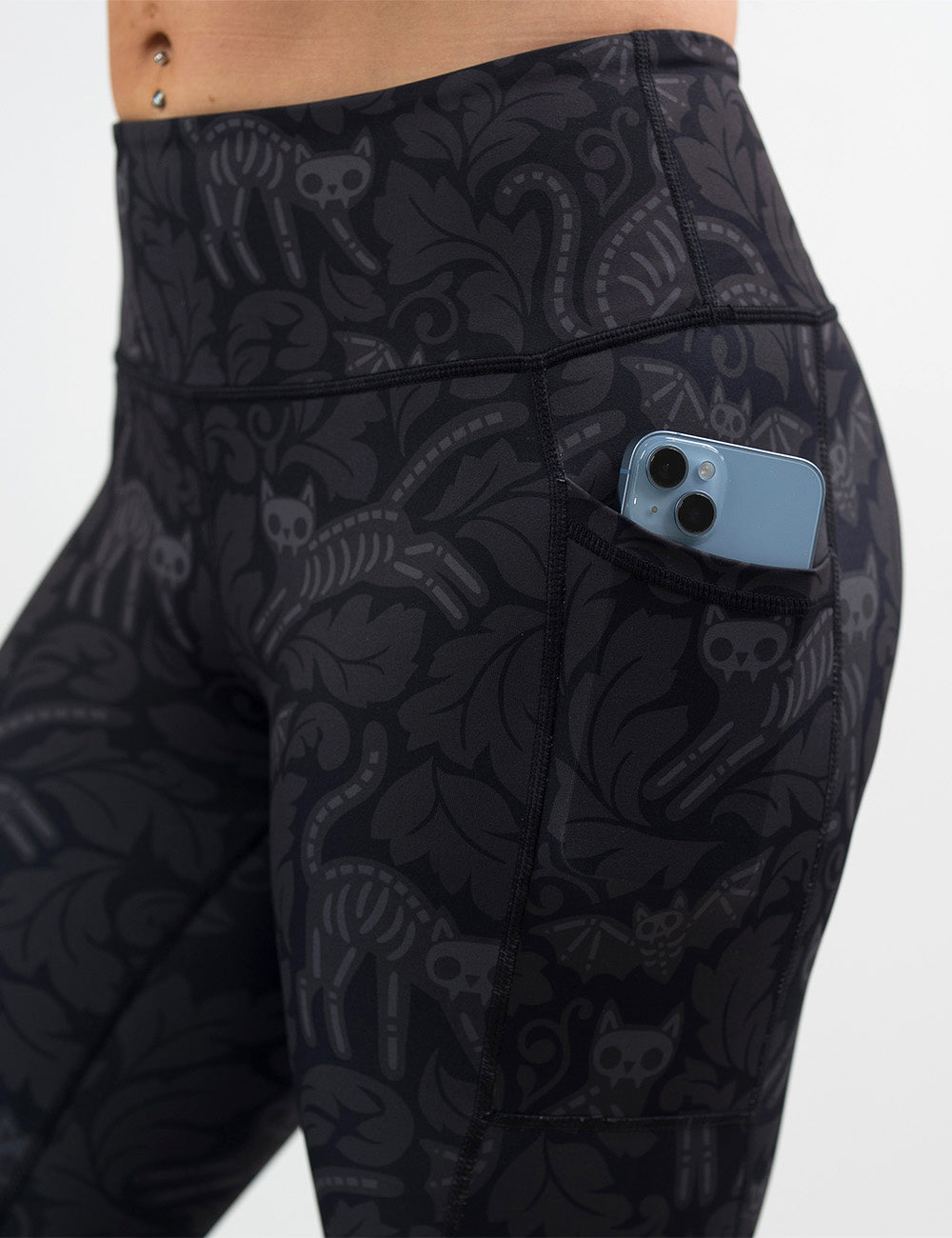 close up of the black and grey bats and cats skeletons with a phone in its pocket against a white background