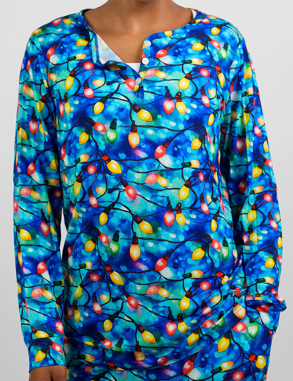 front of the Christmas lights in front of blue and teal background pajama top against a white background
