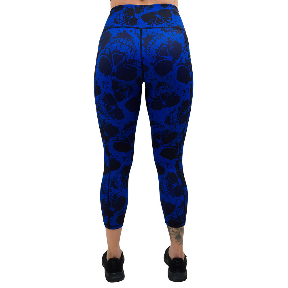 back of the dark skulls against a blue background pattern capri leggings against a white background