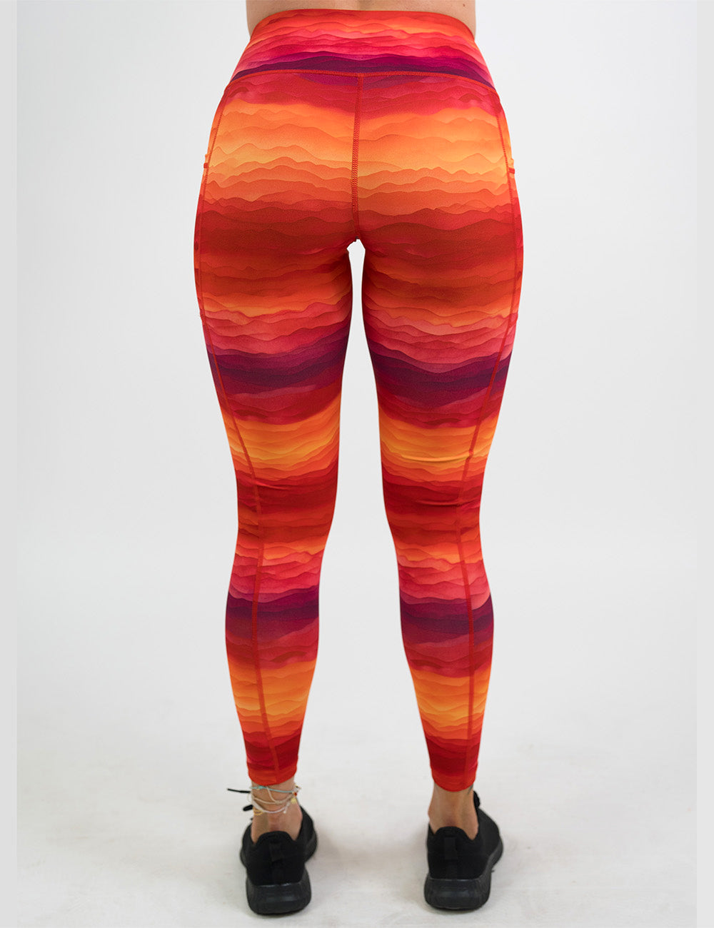 back of the orange, red, and yellow sunset stripes pattern full length leggings against a white background
