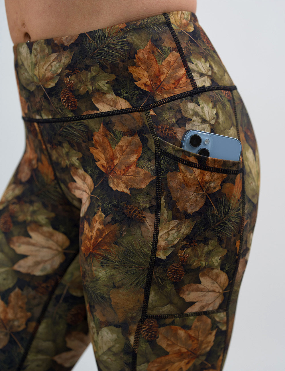 close up of the forest floor covered in leaves leggings with a phone in its pocket