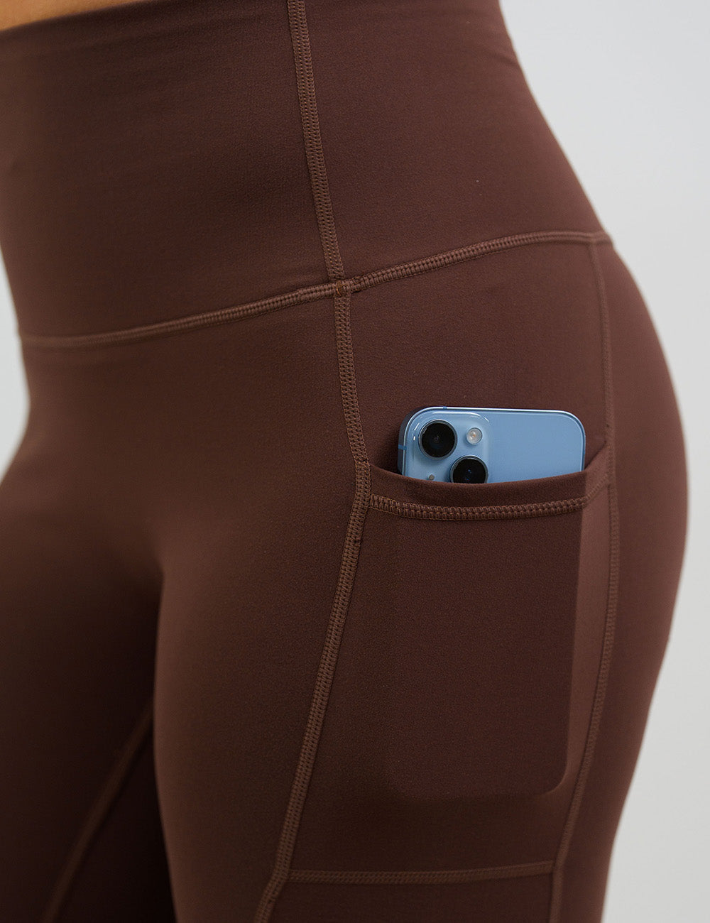 close up of the solid light brown leggings with a phone in its pocket