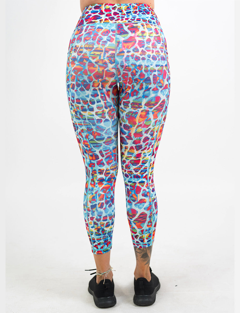 back of the turquoise, coral, pink, orange, purple, and yellow mosaic style pattern full length leggings against a white background