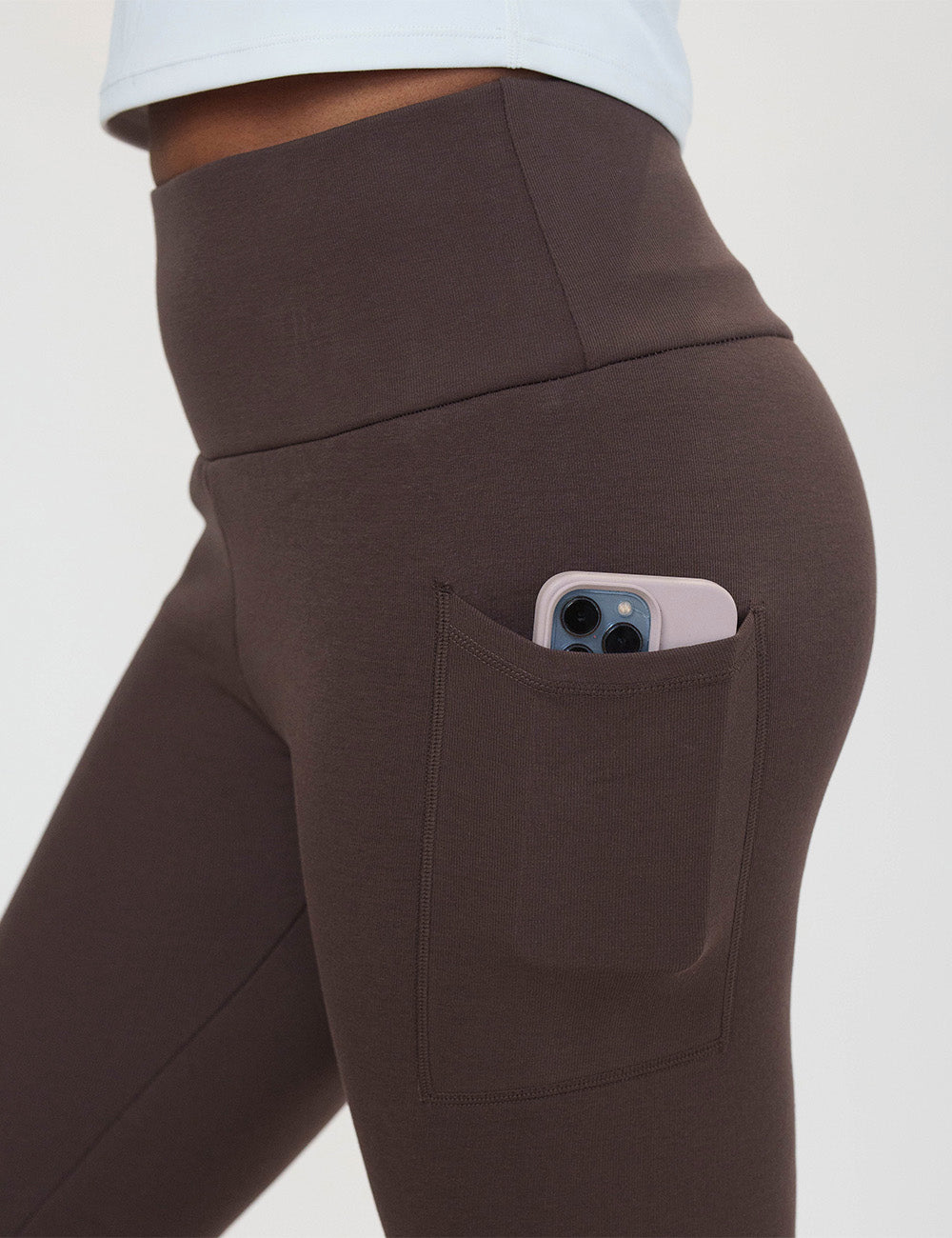 close up of the solid brown fleece lined leggings with a phone in its pocket