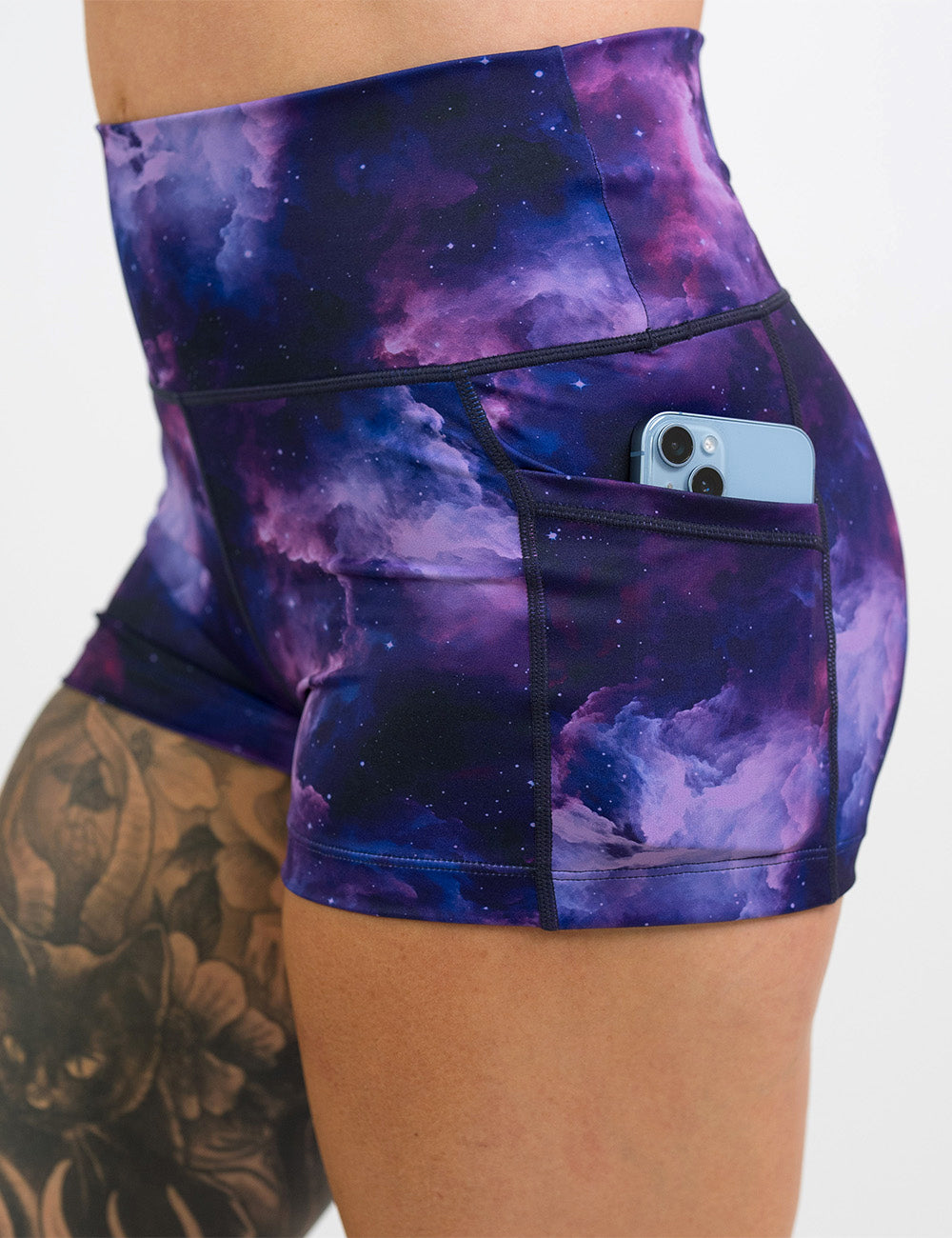 close up of the 2.5 inch purple space patterned shorts with a phone in the pocket