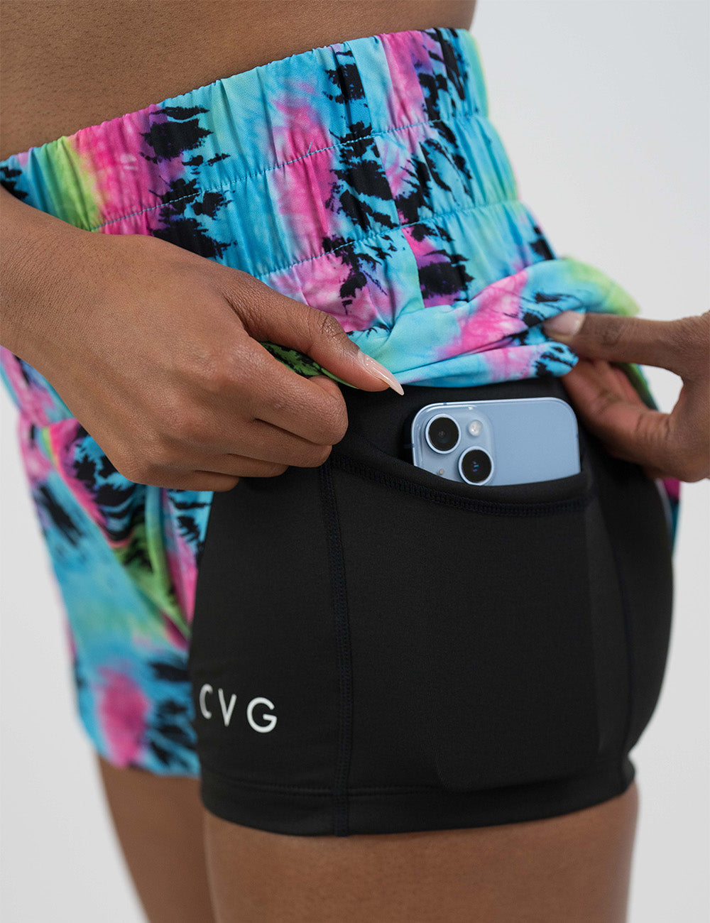 close up of the colorful tie dye day dream shorts pocket with a phone in it