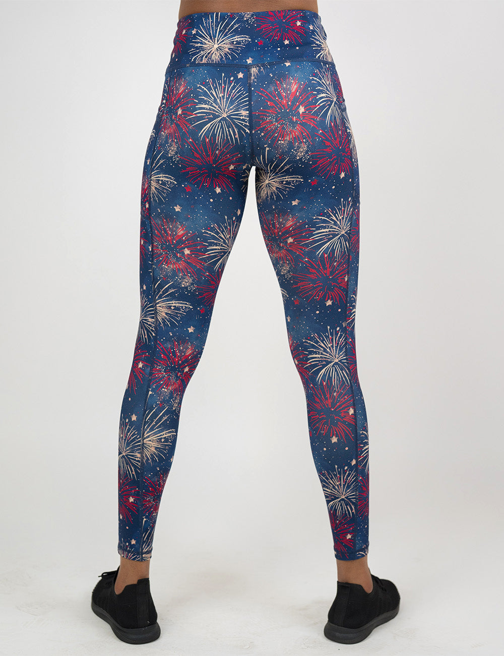 back of the full length blue leggings with a red and white fireworks pattern against a white background