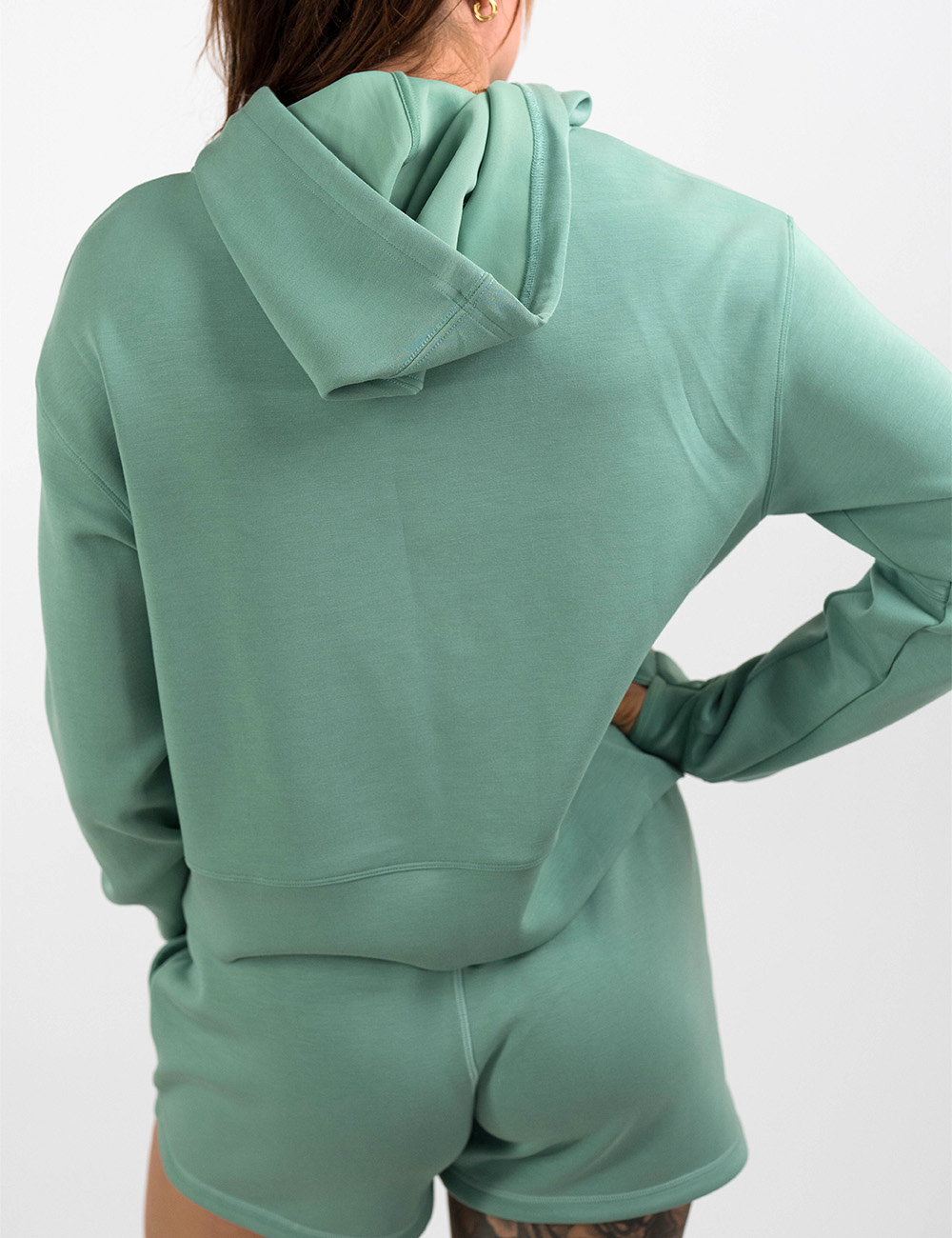 back of the light green hoodie against a white background