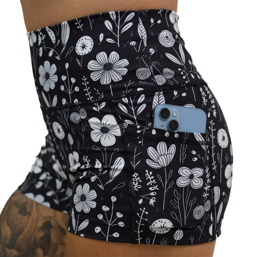 close up of phone in pocket of black and white floral 2.5 inch shorts