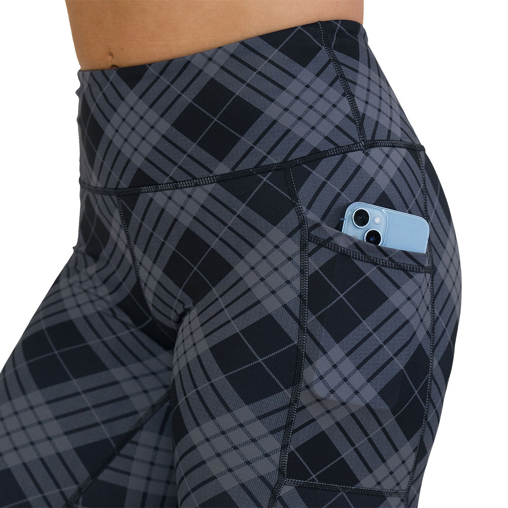 Gray plaid leggings with a pocket holding a phone on a white background