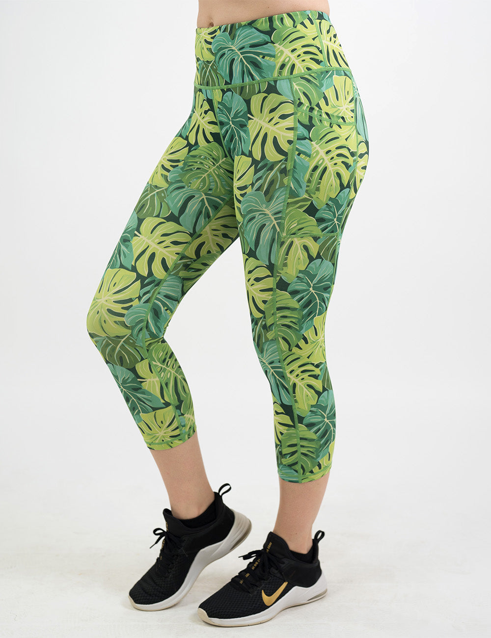 front of the capri green tropical leaves leggings against a white background