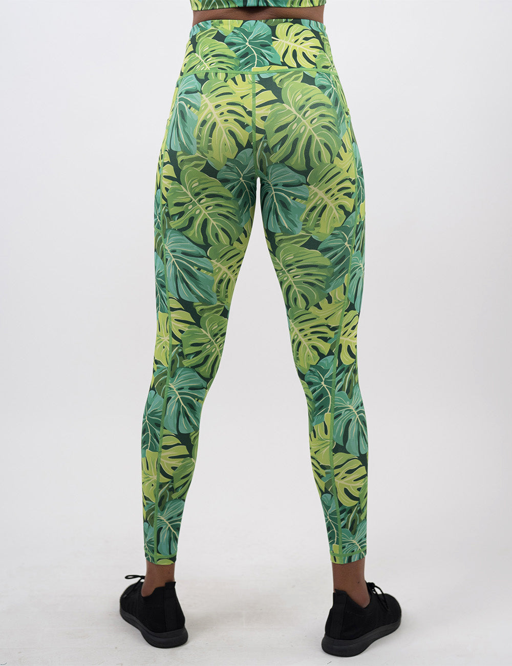back of the full length green tropical leaves leggings against a white background