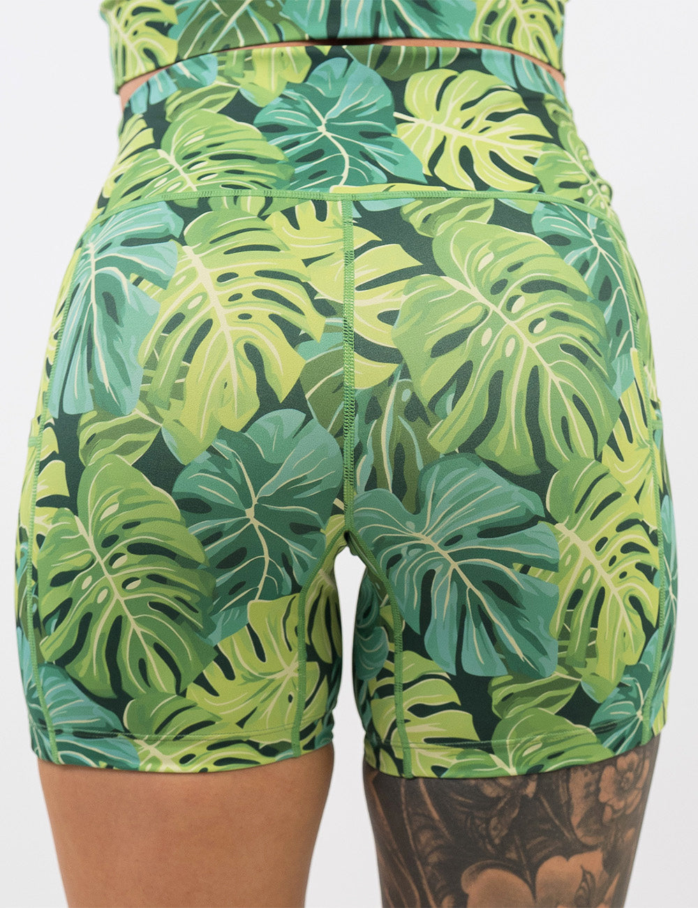 back of the 5 inch green tropical leaves shorts against a white background